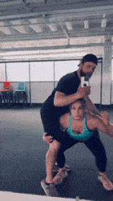 a man is carrying a woman in his arms in a gym .