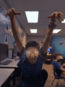 a boy in a blue shirt has his arms up in the air
