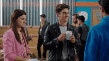 a man in a leather jacket is holding a cup of ice cream and smiling