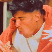 a man is eating a sandwich with a towel around his neck