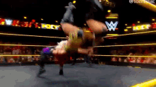 two wrestlers are wrestling in a wrestling ring with a w logo in the background .