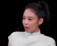 a close up of a woman with a ponytail wearing a white shirt .
