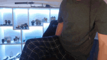 a man in a green shirt sits in front of a display of funko pop figures