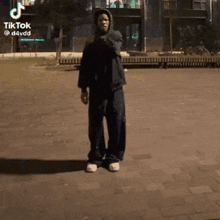 a man in a black hoodie is dancing on a sidewalk with a tiktok watermark