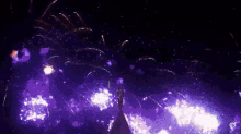 purple fireworks are displayed in the night sky above a tower