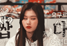 a woman is making a funny face in front of a wall with chinese writing