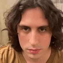 a close up of a man 's face with long hair and a brown shirt