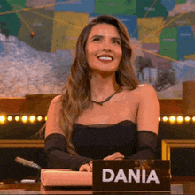 a woman is sitting at a table with a sign that says dania .