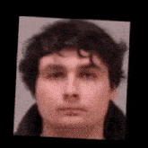 a close up of a man 's face with curly hair and a black jacket .