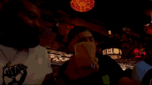 a man wearing a shirt that says ' mrs ' on it drinks from a glass
