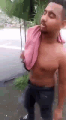 a shirtless man with a pink towel around his neck .