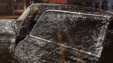 a car is covered in glitter and sparkles and is driving down the street