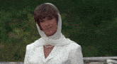 a woman wearing a white scarf around her head looks down