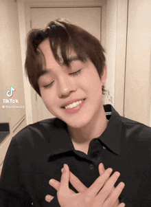 a young man with his hands on his chest has a tiktok sticker on his face