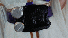 a person wearing a white dress and a purple belt has a black object on their belt that says ' akira '