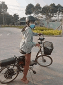 a person wearing a helmet and a mask is riding a bike .