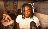 a man wearing headphones is talking into a microphone in front of a pinocchio puppet .