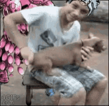 a man is sitting on a chair with a dog in his lap .
