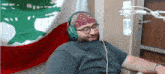 a man wearing headphones and a bandana sitting in front of a microphone