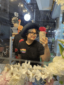 a woman taking a selfie in front of a mirror with flowers in the background