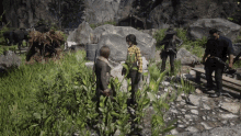 a group of people are standing in a grassy area with a man holding a camera