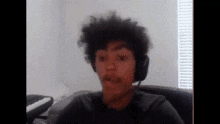 a young man wearing headphones is sitting in front of a window in a room .