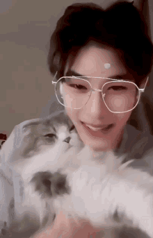 a young man wearing glasses and holding a cat