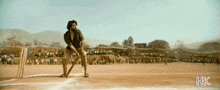 a man is swinging a bat on a cricket field with hkc written on the bottom right