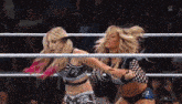 two women are wrestling in a wrestling ring and one is holding the other 's arm .