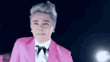 a man with gray hair is wearing a pink suit and tie .