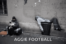 a black and white photo of a homeless man sitting next to a trash can with the words aggie football below it