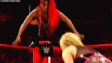 two women are wrestling in a wrestling ring and one of them is wearing a pink top