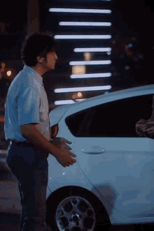 a man standing next to a white car talking to someone
