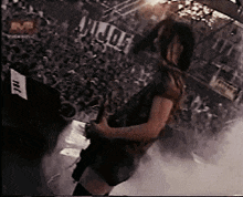 a man playing a guitar in front of a crowd with a sign that says hide on it
