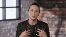 a woman in a black jacket is talking to someone on a television screen .