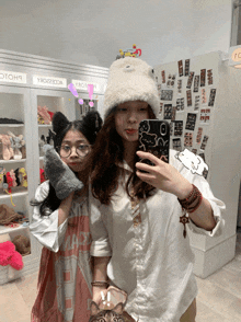 two girls are taking a selfie in front of a wall that says ysq22334a