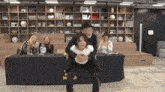 a man is carrying a woman on his back in front of a table with a sign that says ' no smoking '