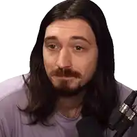 a man with long hair and a beard stands in front of a microphone and looks at the camera