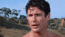 a man without a shirt looks at the camera with a serious look on his face