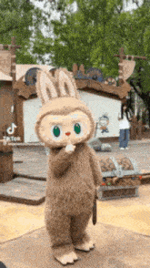 a mascot in a bunny costume is standing on a stage in front of a treasure chest .