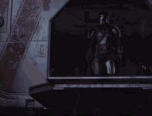 a man in armor is standing in a dark room with a door open