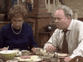 a man and a woman are sitting at a table with food