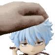 a hand is putting a piece of chocolate on top of a figurine of a boy with blue hair .