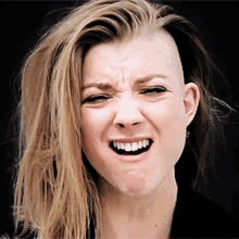 a woman with a shaved head is smiling with her mouth open