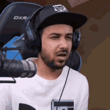 a man wearing headphones and a hat is sitting in front of a dxr gaming chair