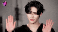 a young man in a black sweater is waving his hands in the air .