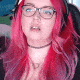 a woman with red hair wearing glasses and a choker necklace