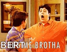 two boys are standing next to each other in a living room . one of the boys is yawning .