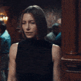 a woman in a black sleeveless top stands in a doorway