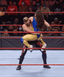 a wrestler is carrying another wrestler in a wrestling ring with the word raw on the back of his pants